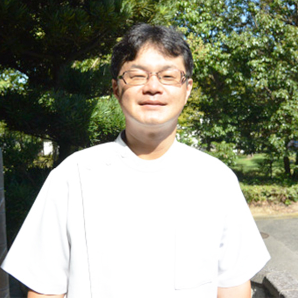 屋外で挨拶する白衣のにしだ鍼灸治療院院長